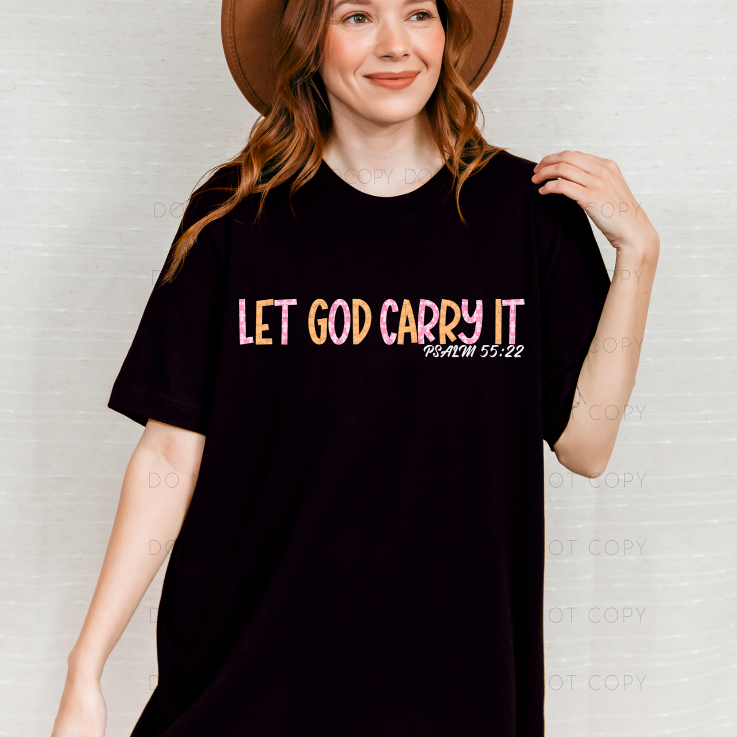 A person wearing a black t-shirt with the text 'LET GOD CARRY IT' printed on the front.