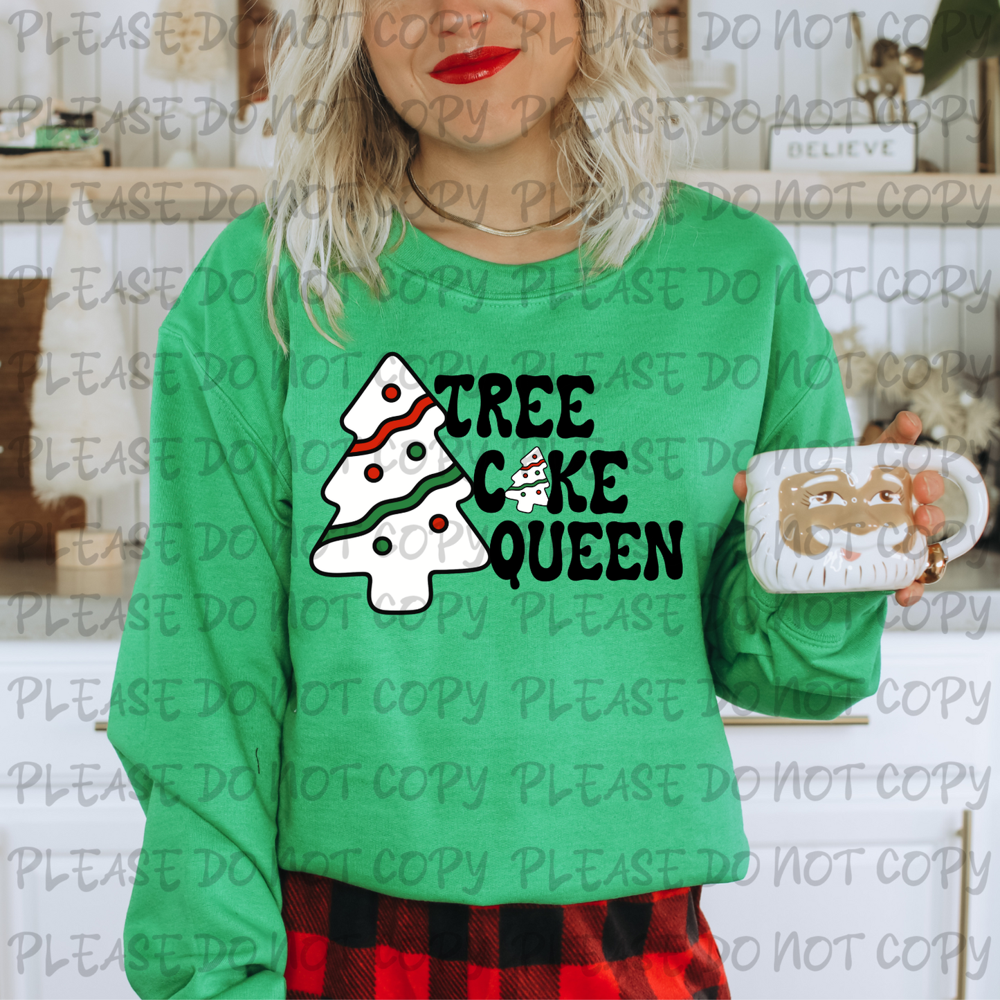 Person wearing a green sweatshirt with 'Tree Cake Queen' design and holding a mug.
