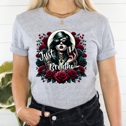 A person wearing a gray unisex t-shirt with a graphic design of a woman's face, roses, and the text 'Just Breathe'.