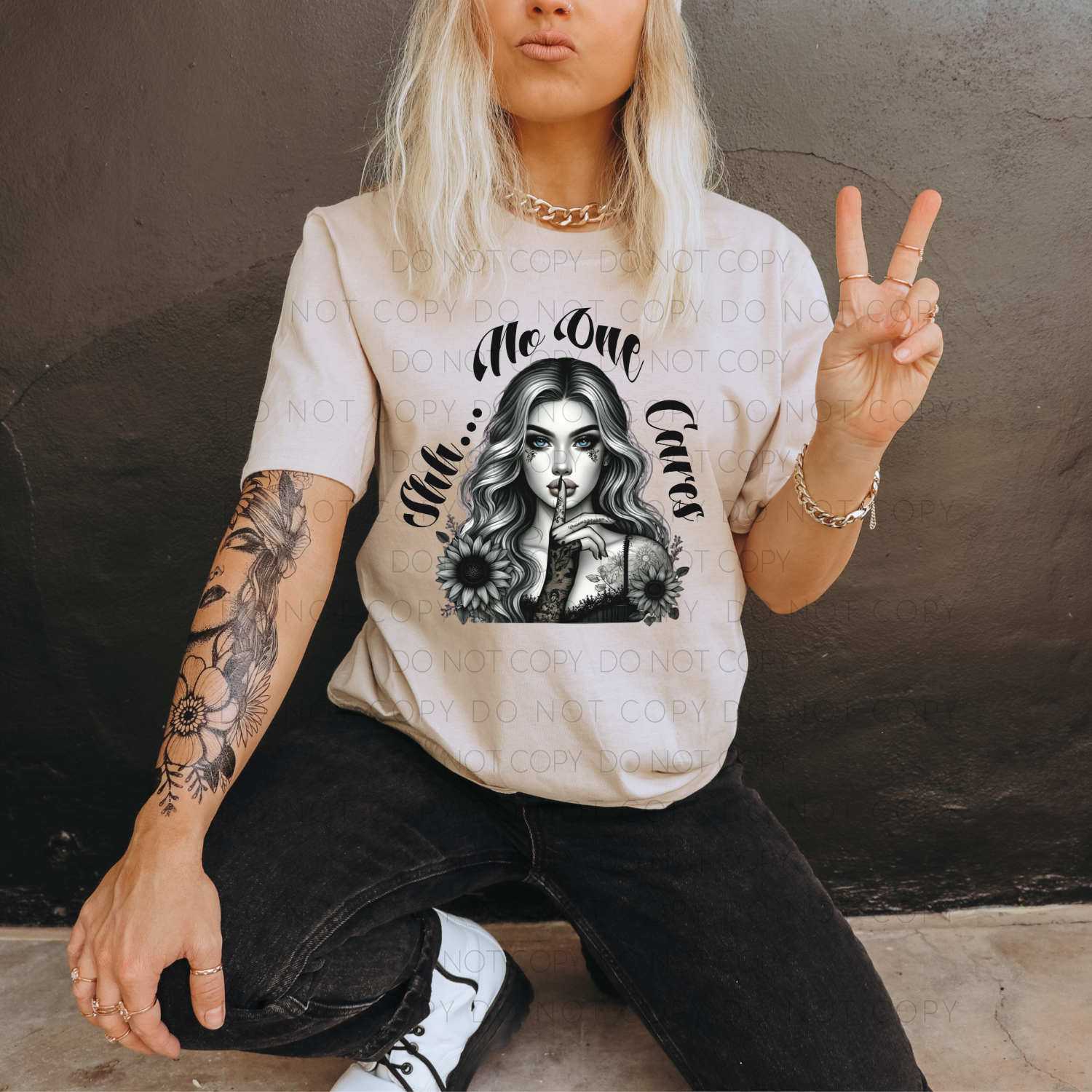 A person posing with a beige t-shirt that has a graphic print of a woman's face and the phrase 'Me Too, Care?'
